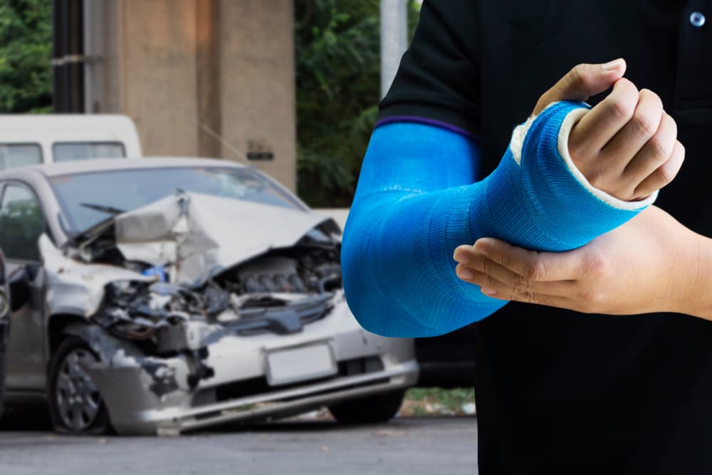 Close up man holding hand with blue bandage as arm injury concept with car accident