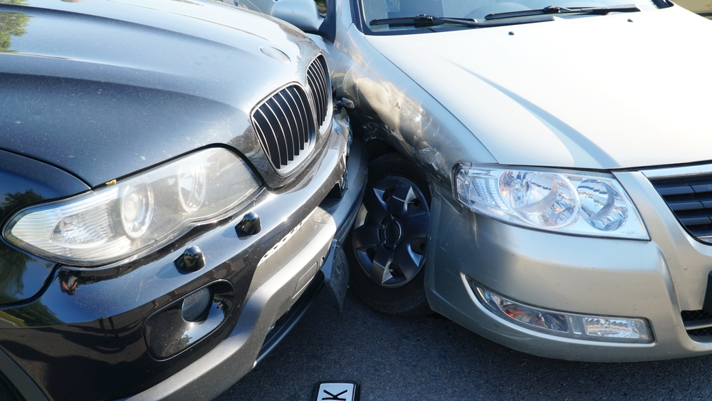 Traffic collision involving damaged vehicles. One car has crashed into a stationary car on a residential street.