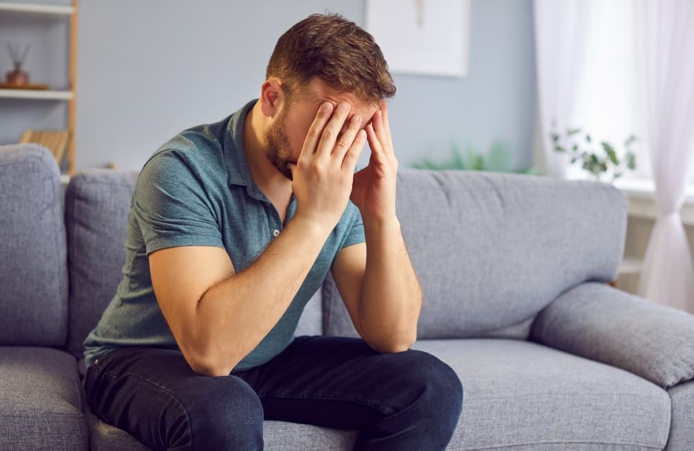 Disappointed man after personal injury holds his head with hands